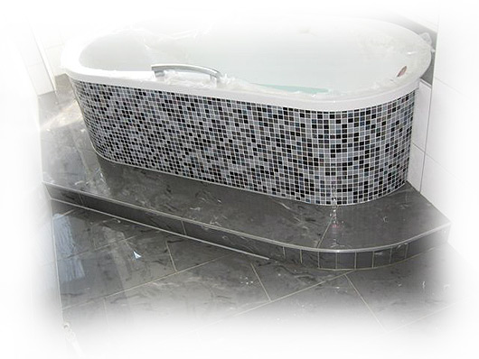 Badewanne mit Mosaikeinfassung und Natursteinfußboden